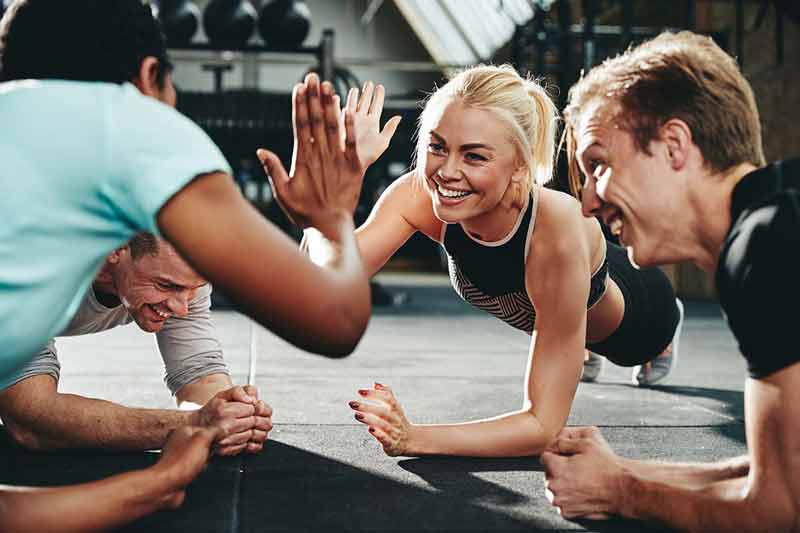 several people doing the plank in a circle, giving a high five
